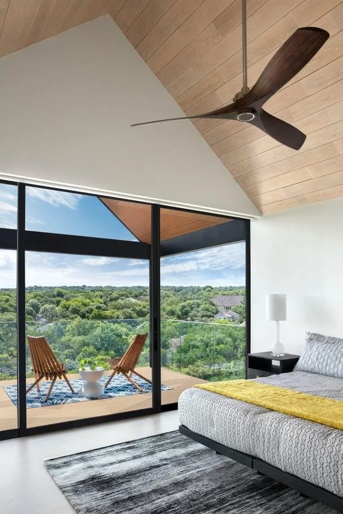 Bedroom of the Barton Hills Residence opening onto a terrace with tree-lined views